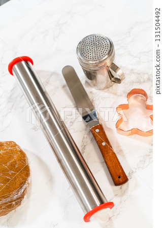 A flat lay of baking tools, including rolling pins and a gingerbread girl cookie cutter, set on a marble surface for preparing Orange Zest Gingerbread Cookies. A flat lay of baking tools, including rolling pins and a gingerbread girl cookie cutter, set on a marble surface for preparing Orange Zest Gingerbread Cookies. 131504492