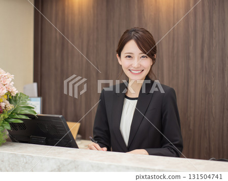 Image of a female staff member in a suit smiling and serving customers over the counter Image of a female staff member in a suit smiling and serving customers over the counter 131504741