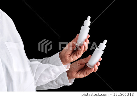 A white serum in the hand of a girl in a white shirt on a black background. Double action. A white serum in the hand of a girl in a white shirt on a black background. Double action. 131505318