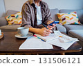 Middle aged woman reviewing expenses, managing personal finances on smartphone mobile app while sitting on couch with coffee in cozy living space. finance planning, financial balance check, budgeting 131506121