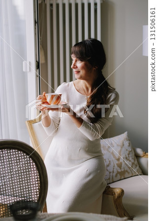 Woman enjoying tea time at home, smiling elegantly Woman enjoying tea time at home, smiling elegantly 131506161