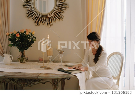 Woman reading book at elegant table with candles 131506193