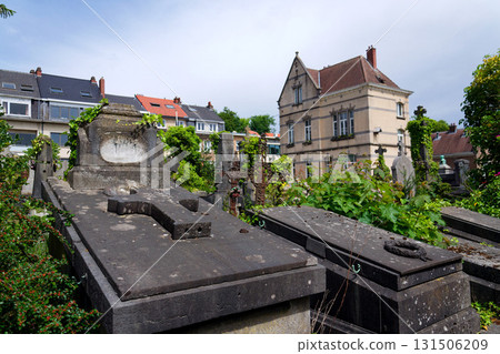 Crucifix on grave at an abandoned Dieweg cemetery overtaken by nature in Brussels, Belgium, sunny day 131506209