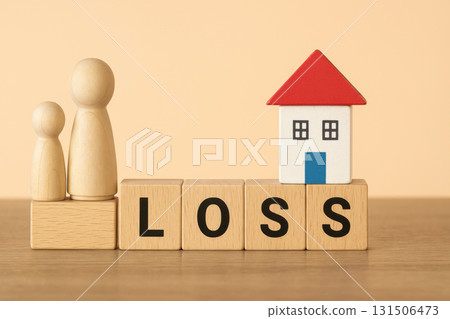 Wooden figurines standing beside small toy house on wooden blocks spelling LOSS financial housing risk concept pastel background 131506473