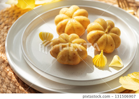 Pumpkin-Shaped Mini Cakes with Cream and Autumn Decor on Woven Placemat Pumpkin-Shaped Mini Cakes with Cream and Autumn Decor on Woven Placemat 131506907