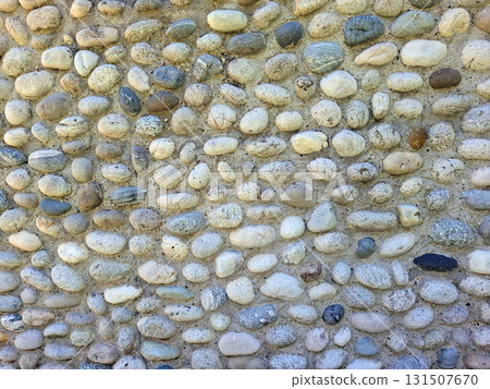 This wall features a natural finish made of smooth sea pebbles, showcasing an attractive and textured surface. The arrangement highlights the pebbles' varied colors and shapes. 131507670
