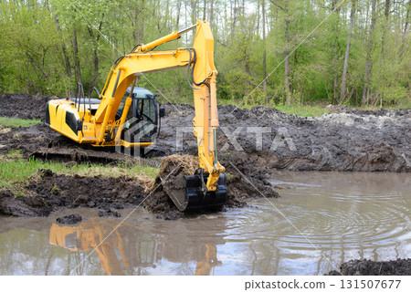 Big powerful excavator digging drainage channel in swamp in countryside Big powerful excavator digging drainage channel in swamp in countryside 131507677