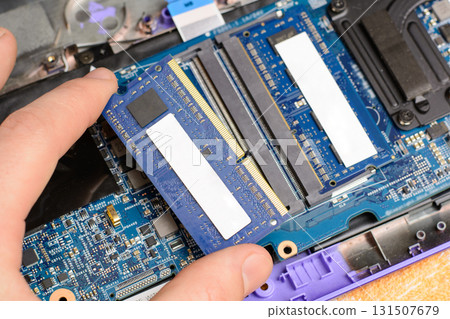 Technician upgrading laptop or personal computer by installing additional RAM chip or memory module 131507679