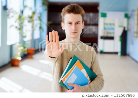 Sad student shows stop sign to the camera to prevent other entrants from entering his university because of bad conditions, inexperienced teaching staff, bribery and malpractice by staff 131507696