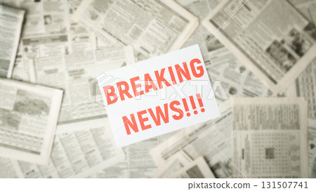 Wide picture of blurred newspapers on the table with the red inscription BREAKING NEWS in the middle on white paper 131507741