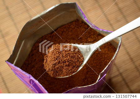Spoon with some ground coffee against a big pack of coffee Spoon with some ground coffee against a big pack of coffee 131507744