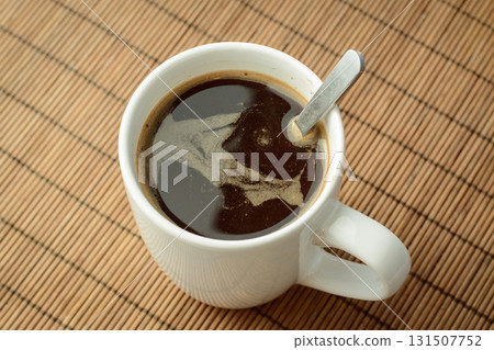 Cup of black coffee with spoon on brown background Cup of black coffee with spoon on brown background 131507752
