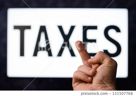 Taxes reform. Frustrated man showing middle finger to a screen with inscription TAXES 131507768