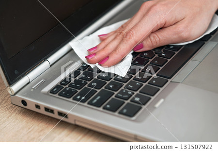 Woman cleaning laptop keyboard with white tissue, detail on her fingers holding paper towel - disinfection concept 131507922