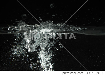 Water splashing as it's poured into aquarium tank, black background 131507949