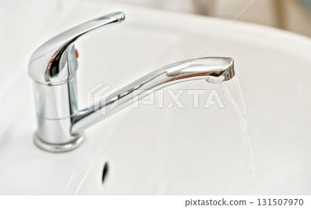 Chrome silver tap faucet with water flowing, closeup detail 131507970
