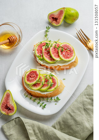 Toasts with fresh figs, cheese, thyme, and honey on a light background. 131508057