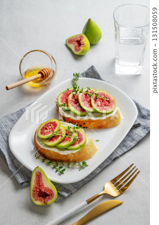 Sweet toasts with fresh figs, cheese, thyme, and honey on a light background. 131508059