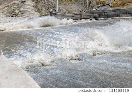 Powerful water splashing against concrete spillway with dentate chutes Powerful water splashing against concrete spillway with dentate chutes 131508119