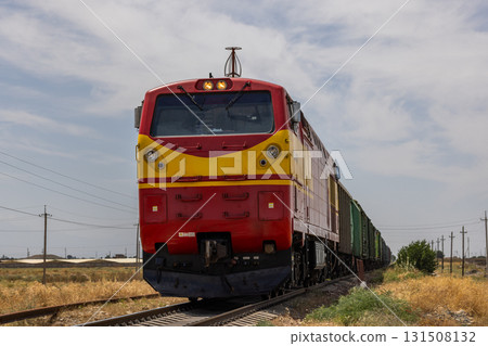 Freight train moving through serene rural landscape during daytime in Kyrgyzstan 131508132