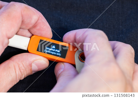 hardware Bitcoin wallet with message Invalid PIN in hands of Caucasian male 131508143