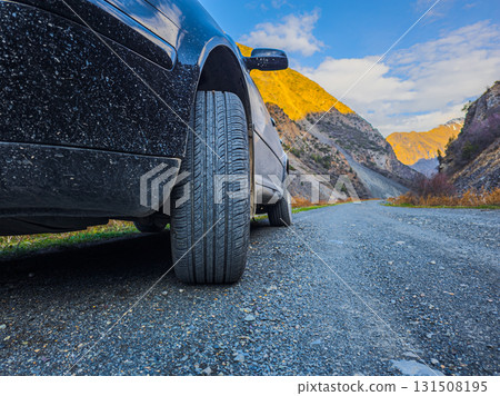 Car parked on muddy gravel road in mountainous region 131508195