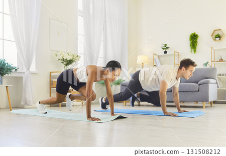 Fitness workout on mats of couple at home, doing cardio and endurance training 131508212
