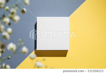 White cube, podium or box with shadow on diagonally divided yellow and blue background 131508215