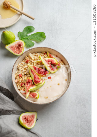 Natural yogurt with granola, figs and honey in a bowl on a light background 131508260