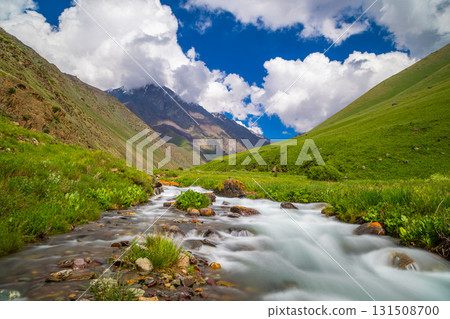 Serene mountain valley with flowing stream and rocks in Kyrgyzstan Serene mountain valley with flowing stream and rocks in Kyrgyzstan 131508700