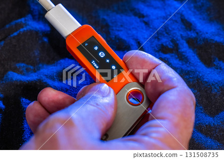 Hand holding orange hardware wallet with Tron symbol 131508735