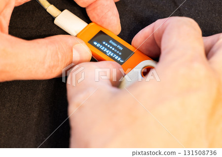 Adult man holding orange electronic device indoors Adult man holding orange electronic device indoors 131508736