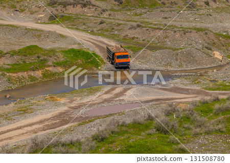 Truck loaded with rocks driving through stream in rural mountainous area Truck loaded with rocks driving through stream in rural mountainous area 131508780