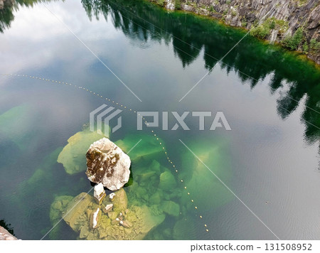 A rock is in the middle of a body of water. 131508952