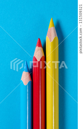 Three colored wooden pencils on a blue background 131509321