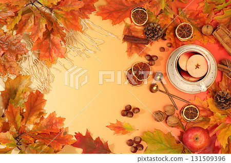 Autumn abstract composition with cup of mulled wine or tea, maple leaves, pine cones, nuts, cinnamon, star anise and dried oranges, still life and Thanksgiving concept, seasonal background and banner 131509396