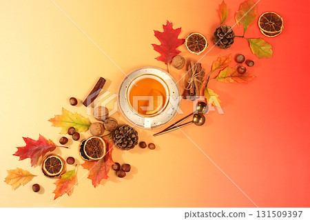 Bright autumn banner with cup of tea or mulled wine, maple leaves, pine cones, nuts, cinnamon, star anise and dried oranges, abstract seasonal composition and still life, Thanksgiving concept, 131509397