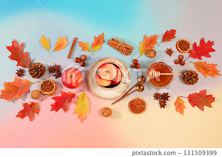 Autumn abstract composition with cup of mulled wine or tea, maple leaves, pine cones, nuts, cinnamon, star anise and dried oranges, still life and Thanksgiving concept, seasonal background and banner 131509399