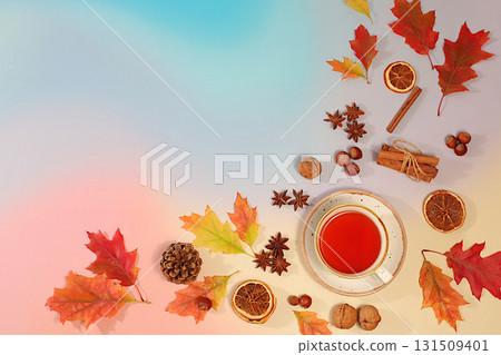 Bright autumn flyer with a cup of tea or mulled wine, maple leaves, pine cones, nuts, cinnamon, star anise and dried oranges, abstract seasonal composition and still life, Thanksgiving concept, 131509401