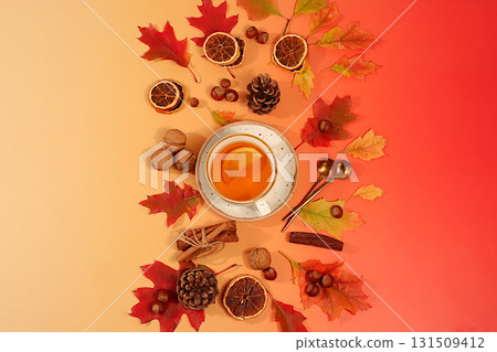 Bright autumn flyer with a cup of tea or mulled wine, maple leaves, pine cones, nuts, cinnamon, star anise and dried oranges, abstract seasonal composition and still life, Thanksgiving concept, 131509412