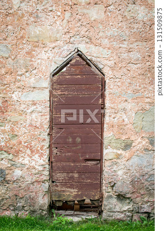 Old wooden door with peeling paint set in a textured stone wall of a historic building Old wooden door with peeling paint set in a textured stone wall of a historic building 131509875