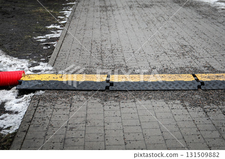 Red Pipe with Yellow Cable Protector on Wet Ground 131509882