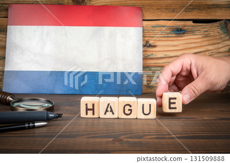 Wooden blocks arranged to spell the word Hague placed on a wooden table with the Dutch flag in the Wooden blocks arranged to spell the word Hague placed on a wooden table with the Dutch flag in the 131509888