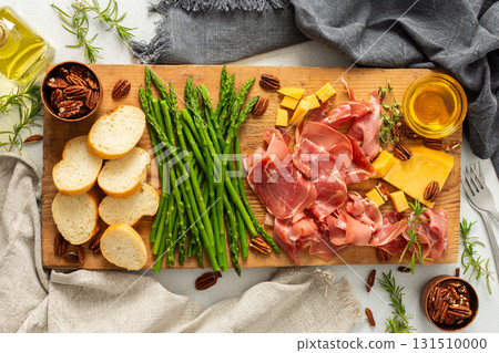 Indulge in a beautifully arranged charcuterie board with vibrant asparagus, savory cured meats, assorted cheeses, and freshly toasted bread, ideal for sharing with friends Indulge in a beautifully arranged charcuterie board with vibrant asparagus, savory cured meats, assorted cheeses, and freshly toasted bread, ideal for sharing with friends 131510000