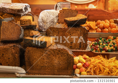 Large slices of traditional fruitcake displayed with candied fruits at Christmas holiday market. Concept of bakery sweetness, fruitcake tradition, festive dessert Large slices of traditional fruitcake displayed with candied fruits at Christmas holiday market. Concept of bakery sweetness, fruitcake tradition, festive dessert 131510301