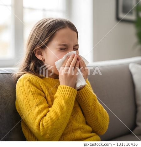 Young girl sneezing into a tissue on a sofa Young girl sneezing into a tissue on a sofa 131510416