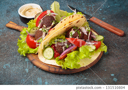 Falafel tacos with fresh vegetables and creamy tahini sauce served with hummus Falafel tacos with fresh vegetables and creamy tahini sauce served with hummus 131510804
