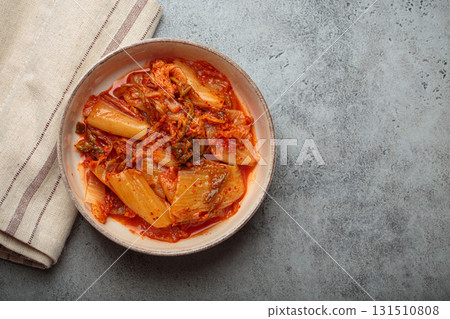 Spicy traditional korean kimchi in serving bowl on grey background top view, space for text Spicy traditional korean kimchi in serving bowl on grey background top view, space for text 131510808