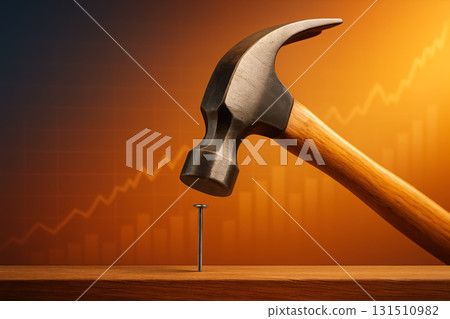 Hammer striking a nail into wood with a background showing upward financial trends during sunset 131510982
