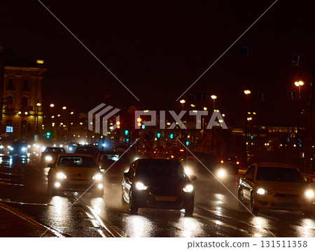 Bright night traffic: blurred car headlights on a wet street in the city center 131511358
